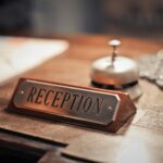 Close-up of a hotel reception desk showcasing a service bell and signage, emphasizing hospitality.